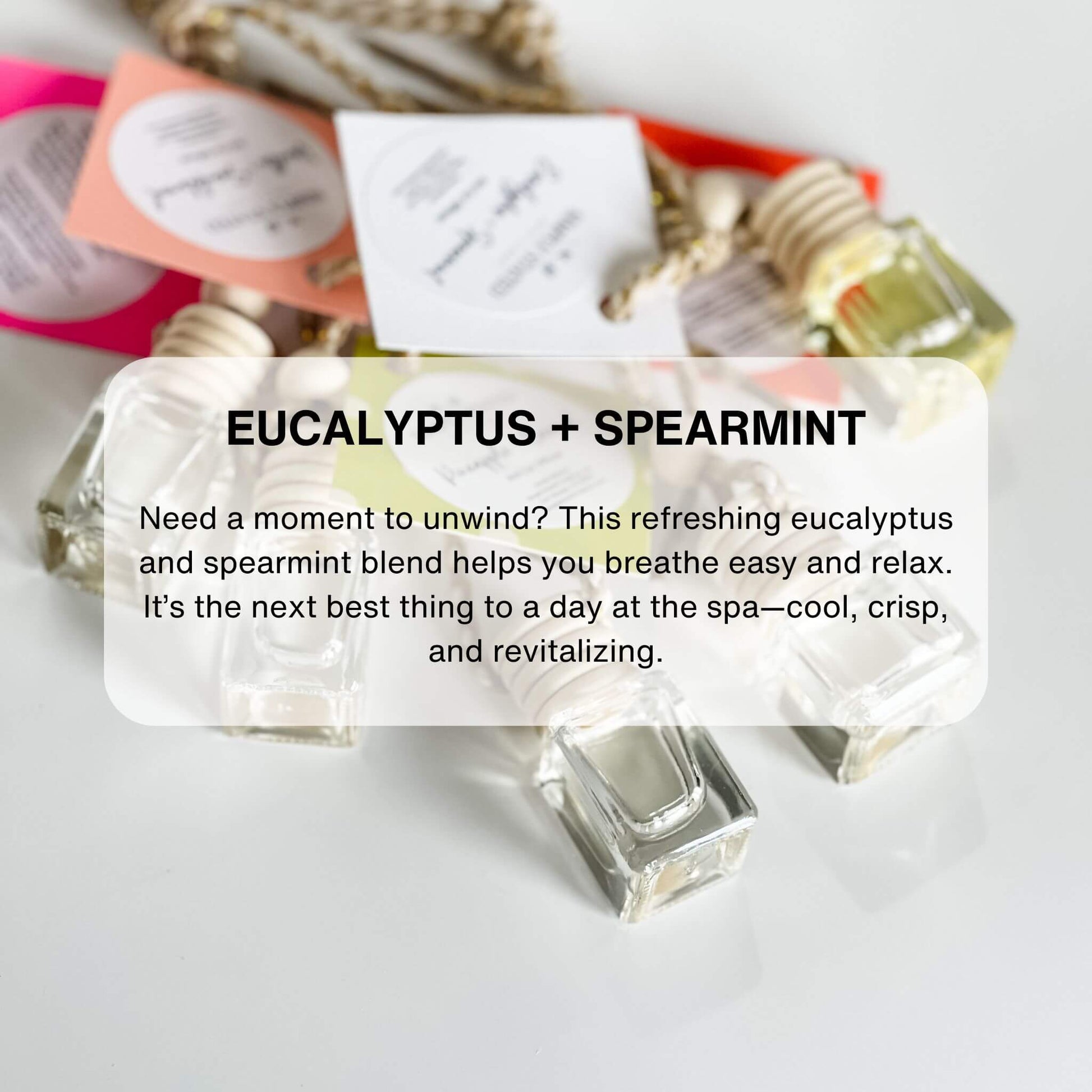 A set of car diffusers with clear glass jars and wooden lids, hanging from gold-colored chains.