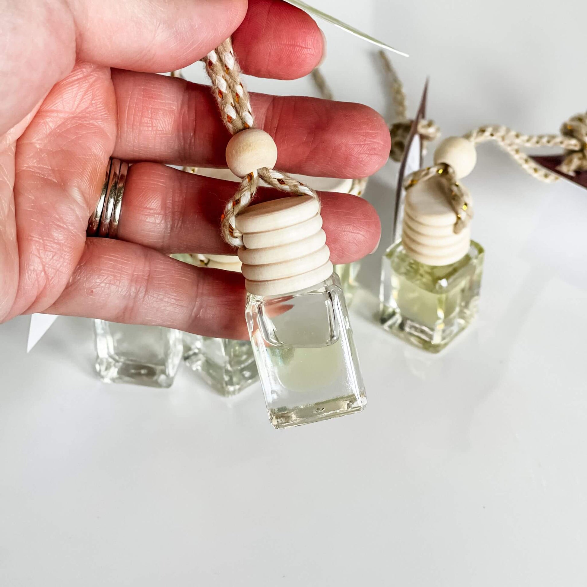 Close-up of hand holding Signature Car Diffuser bottle with wooden top