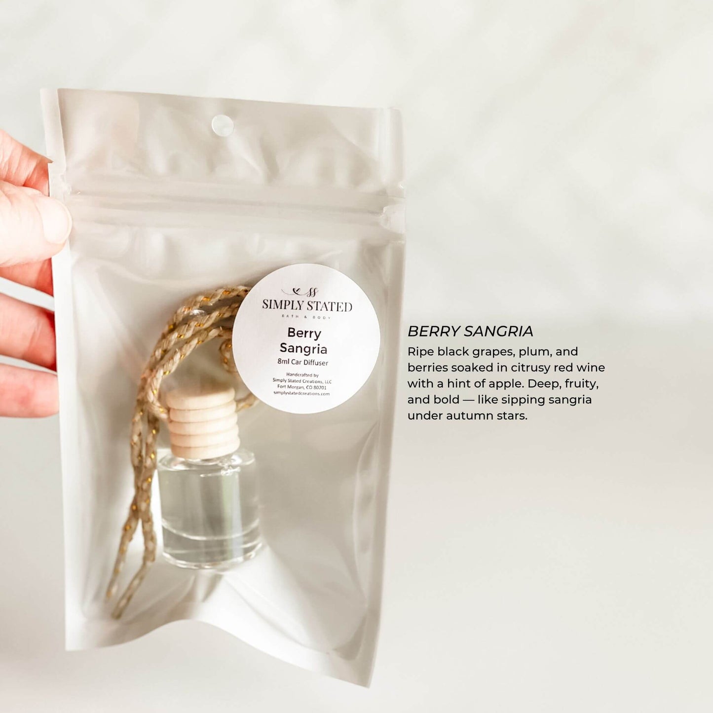 Hand holding a berry sangria diffuser packaging with a white background
