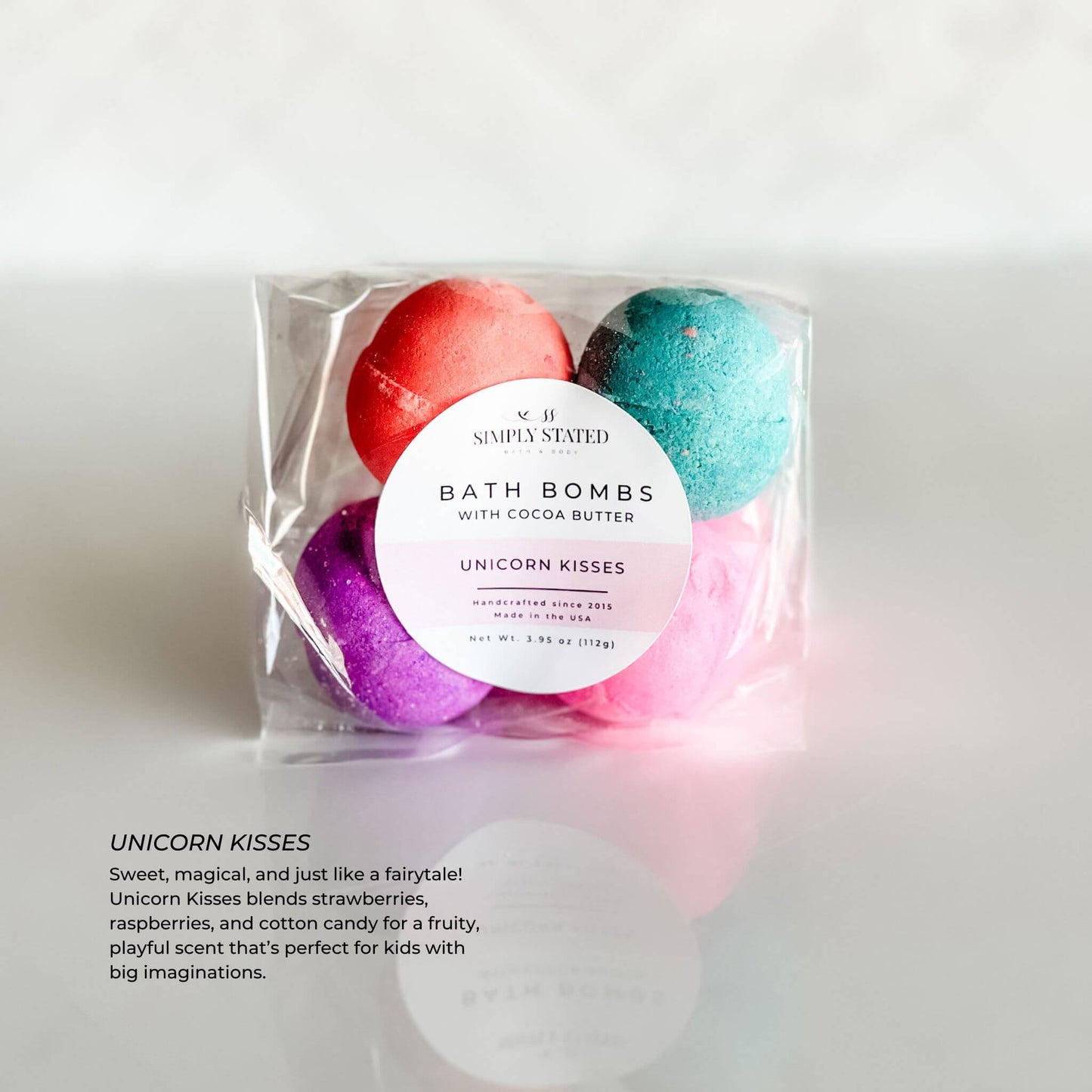 Simply Stated Kids Line Bath Bomb Pack in Unicorn Kisses scent, showing colorful pink, blue, and purple bath bombs, packaged with a pink-accented circular label.