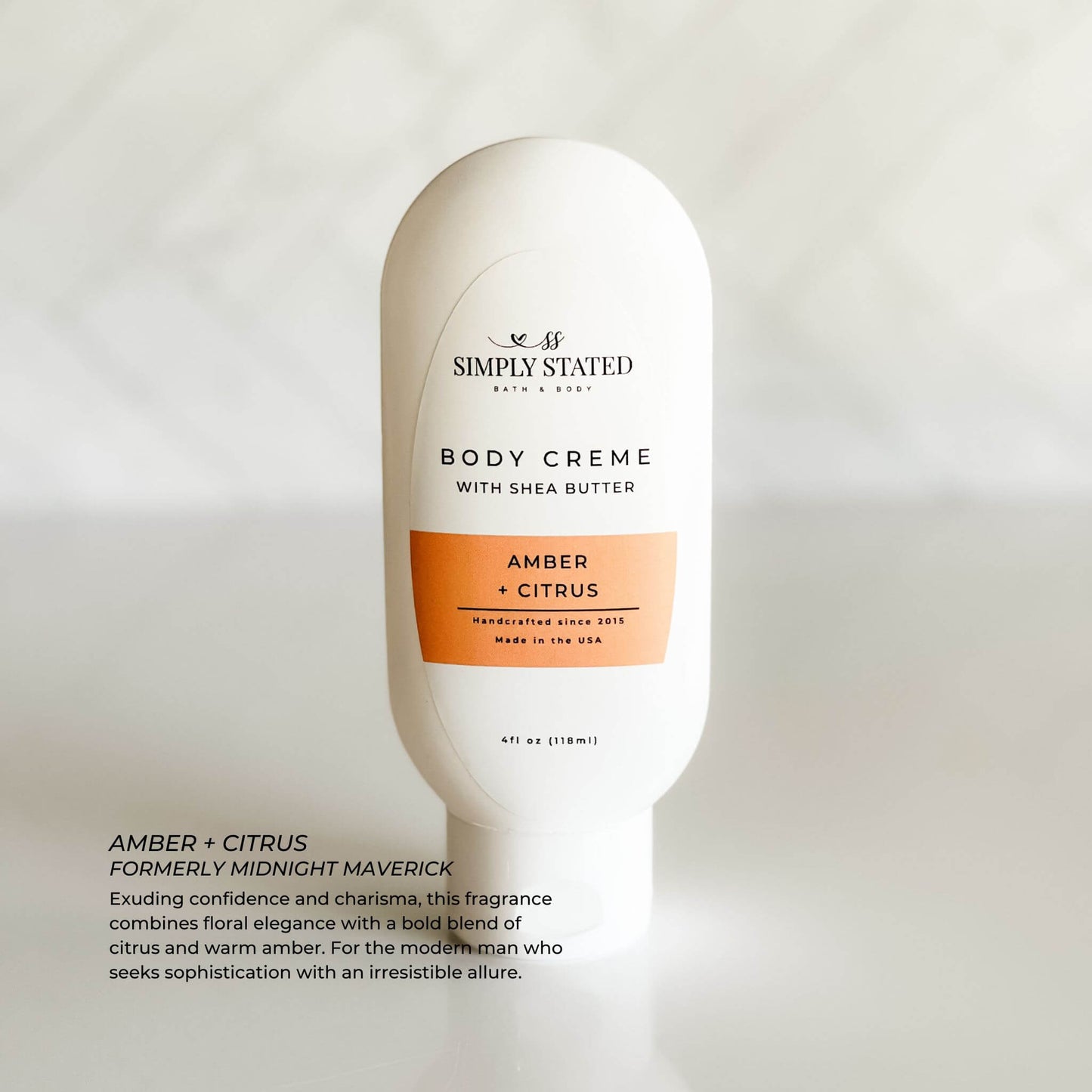 Close-up of Amber + Citrus 4 oz body creme bottle, a sleek squeeze tube with modern label.