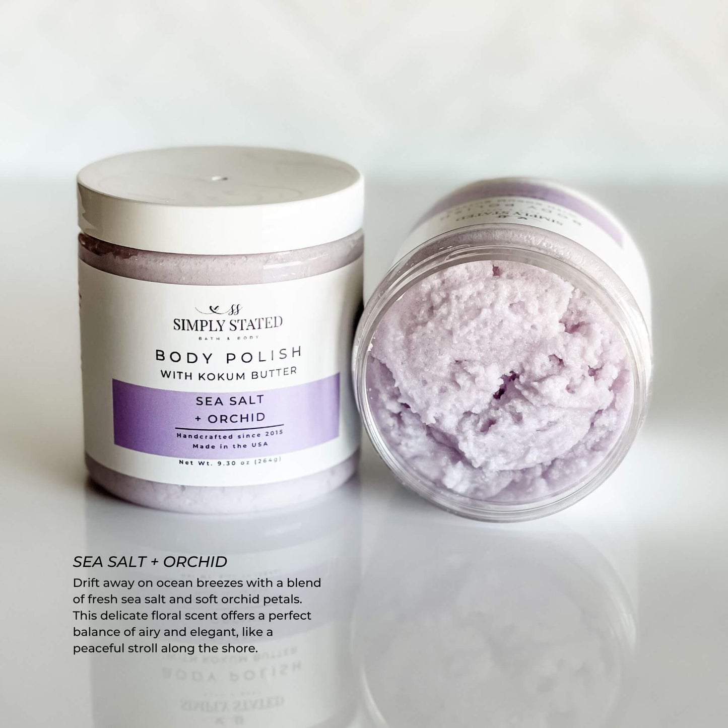Simply Stated Body Polish in Sea Salt + Orchid scent, a delicate floral scrub blending fresh sea salt and soft orchid petals for a luxurious exfoliation experience. 9.3 oz jar with updated label design.