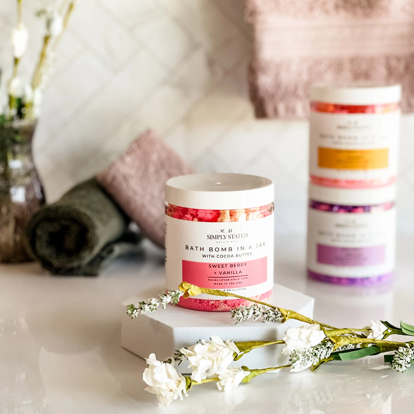 Bath bomb in a jar with decorative flowers on a marble surface