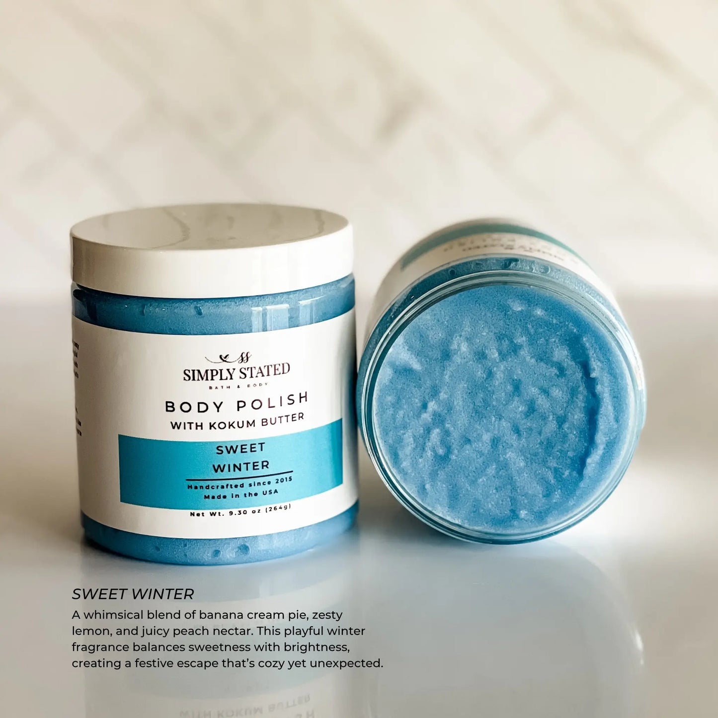 Body polish jar with lid off, showing blue scrub, on a light background