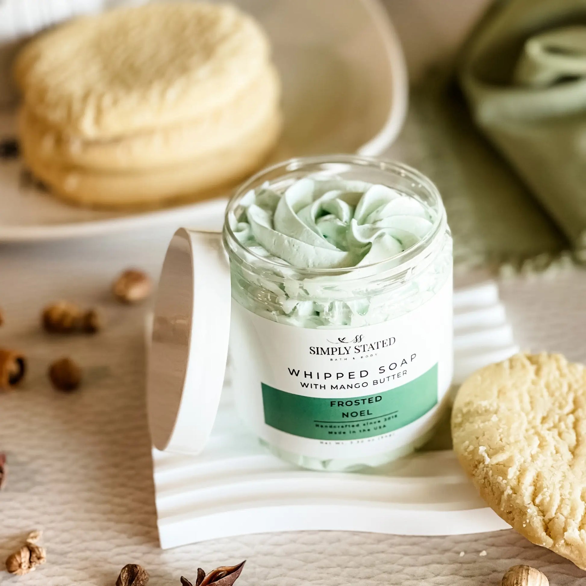 Whipped soap in a glass jar with a decorative label on a wooden surface.